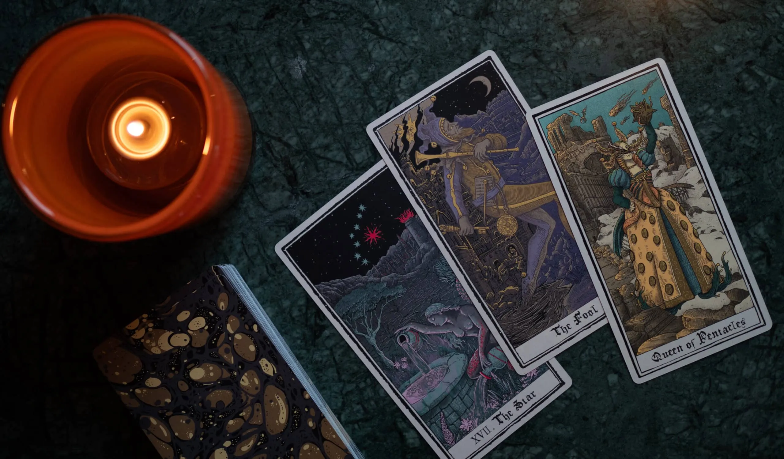 Three tarot cards laid out beside a candle