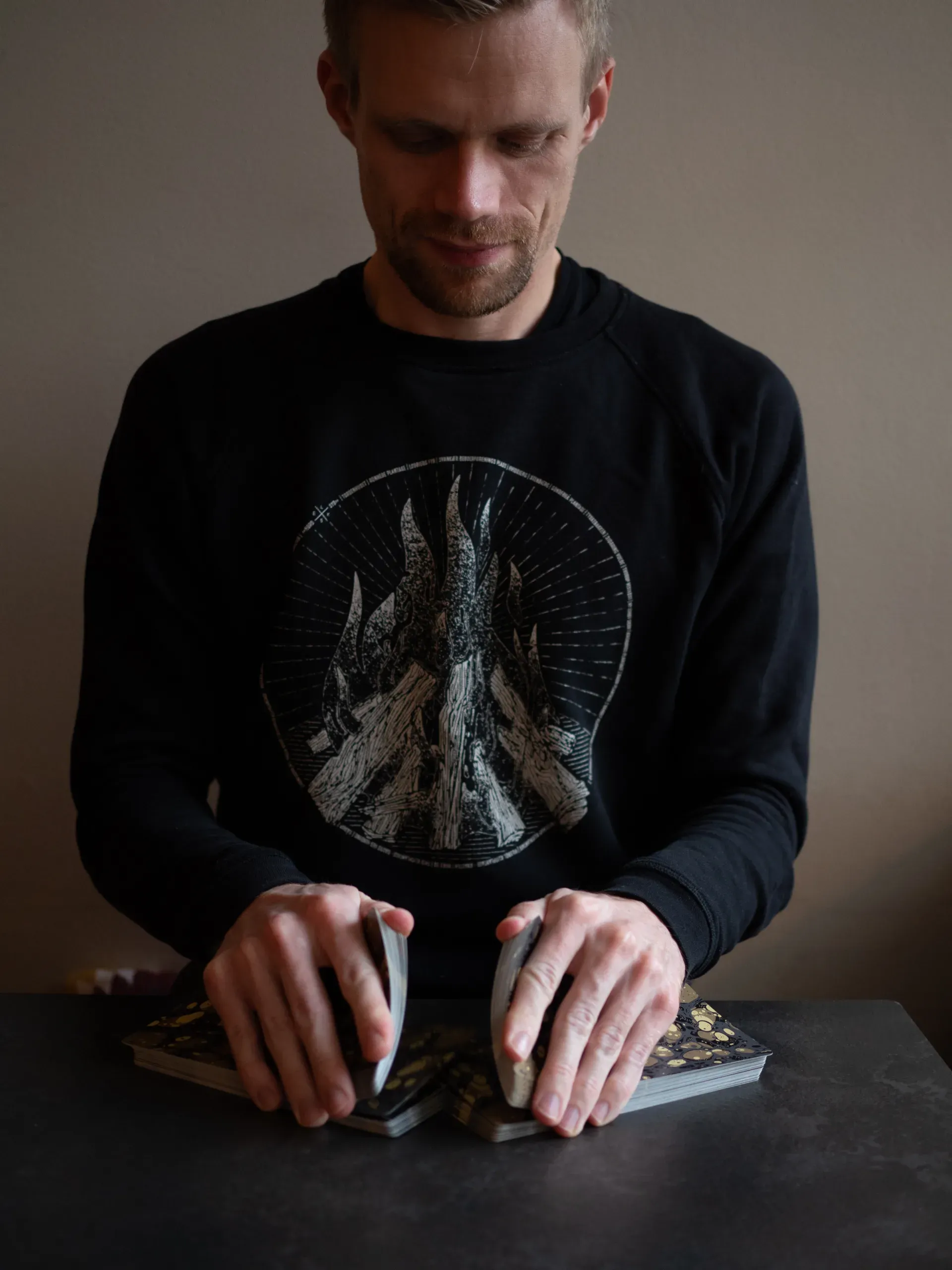 Mark shuffling a tarot deck at a dark table
